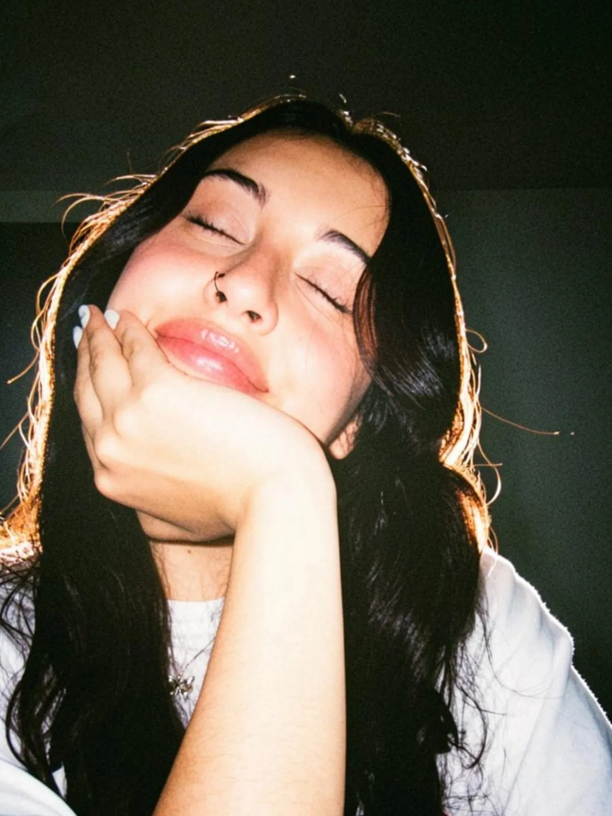 Retrato de Camila sonriendo con los ojos cerrados y la mano en la mejilla